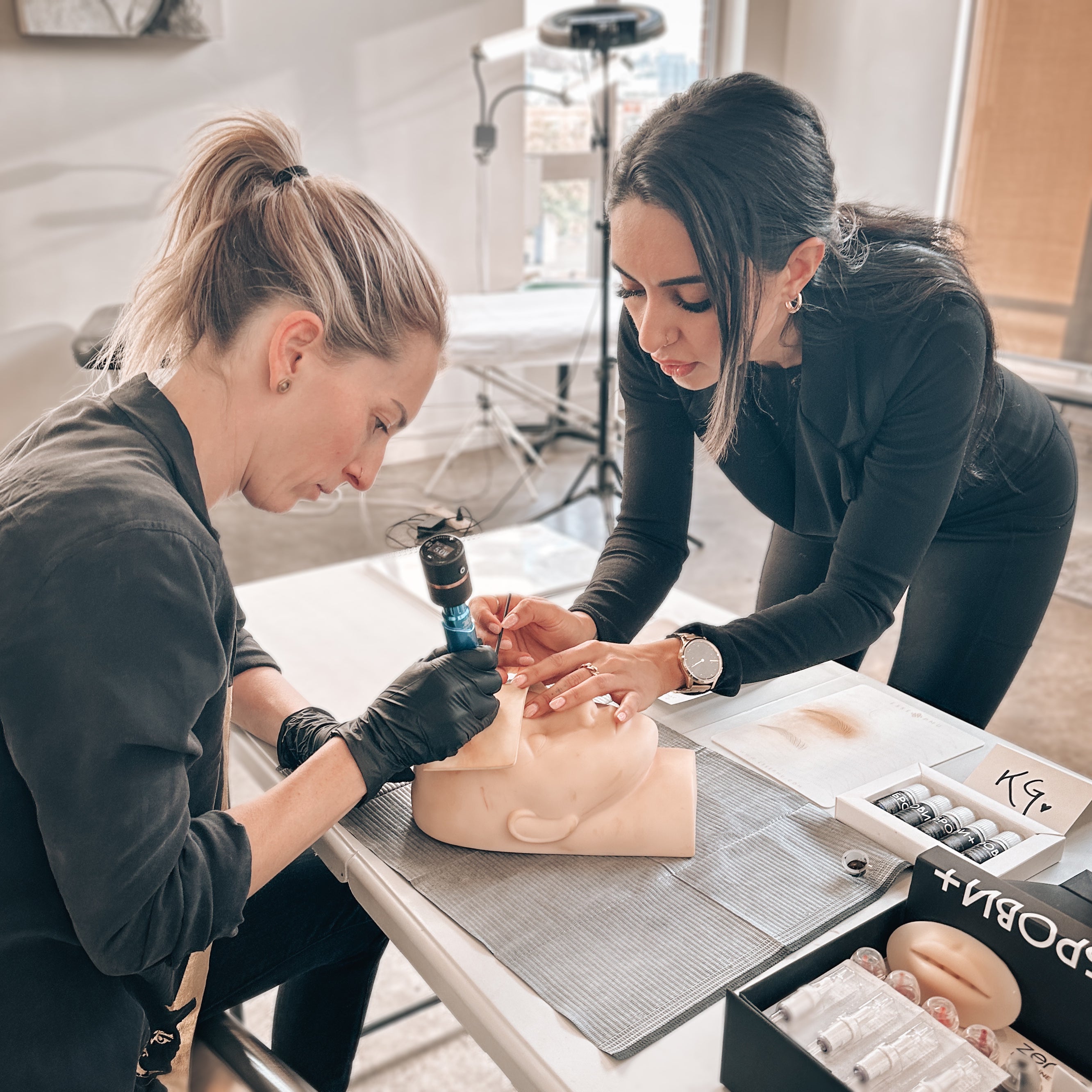 Rouge Ink's Rojin aids student practicing tattooing technique.