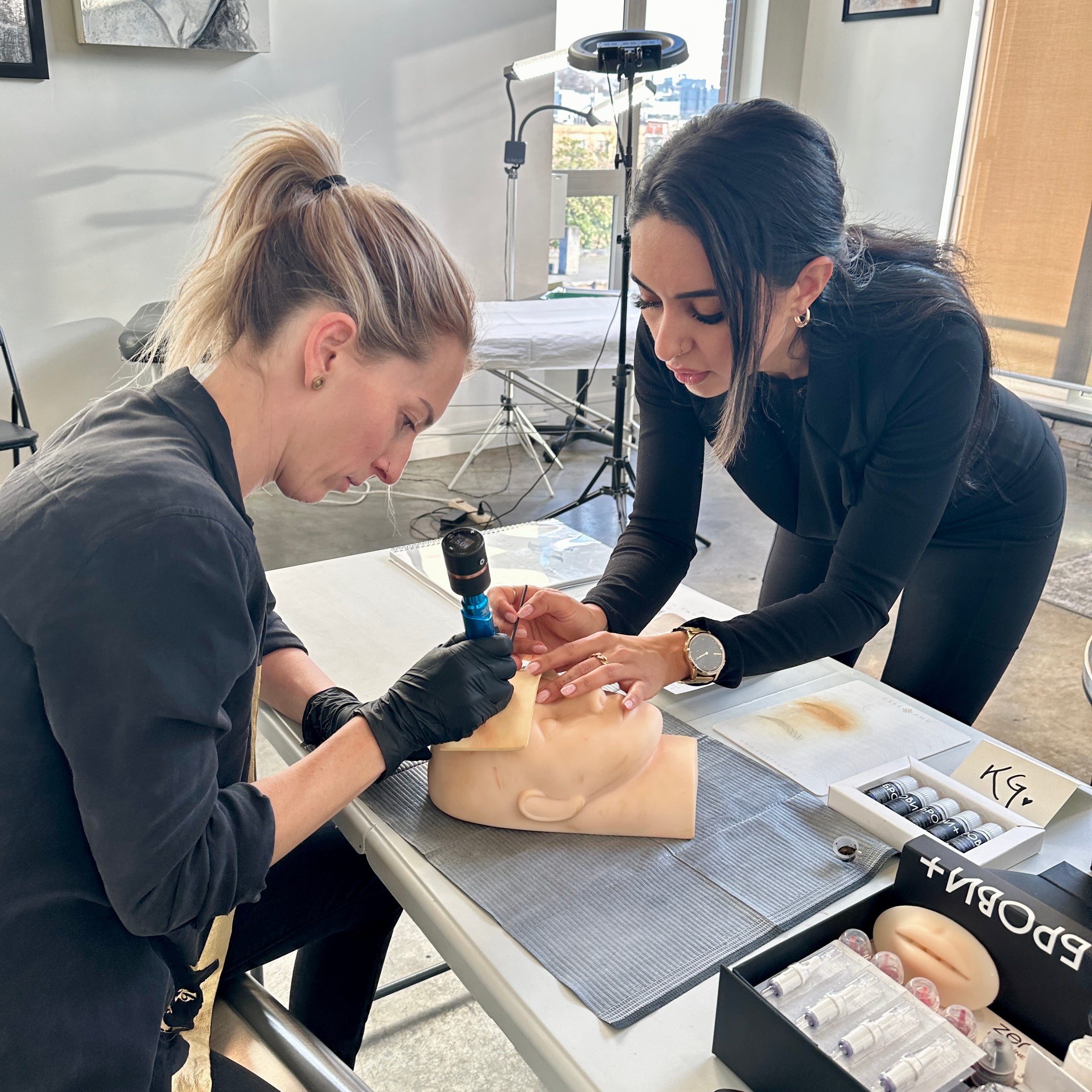 Rouge Ink's Rojin aids student practicing tattooing technique.