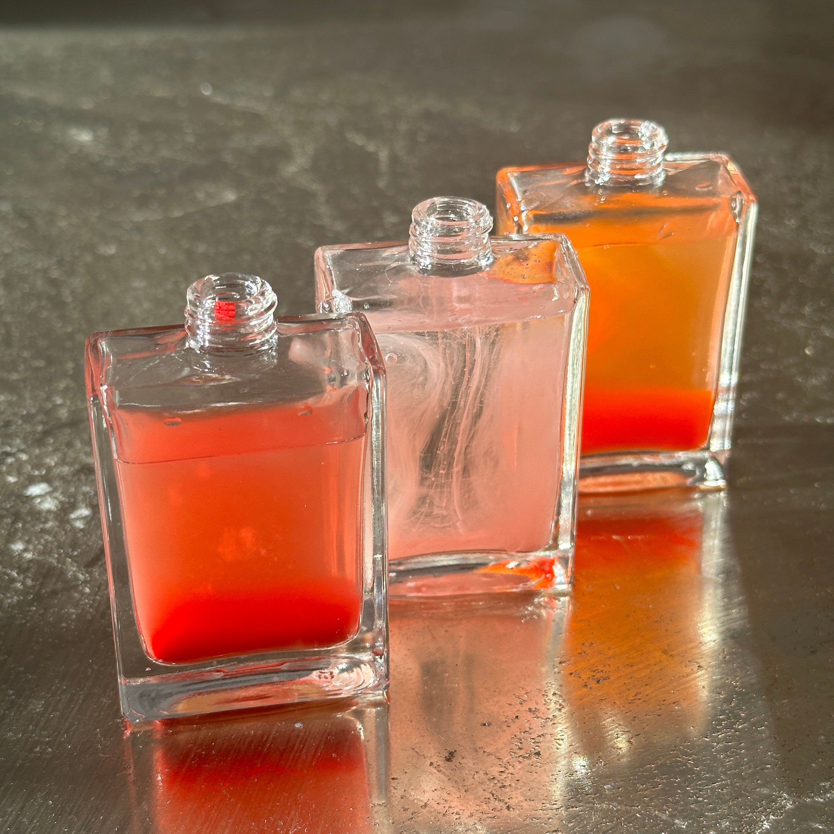 Up-close of three glass cosmetic bottles.