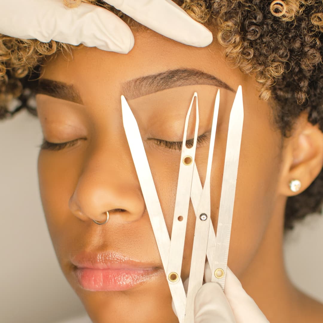 Close-up of brow shaping procedure at Rouge Ink, using precision tools to enhance brow symmetry and definition.