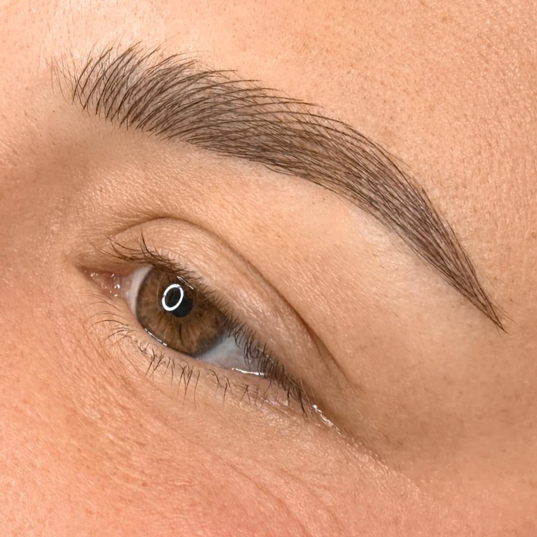 Close-up of microblading eyebrow treatment at Rouge Ink, showcasing fine hair-like strokes for natural brow enhancement.