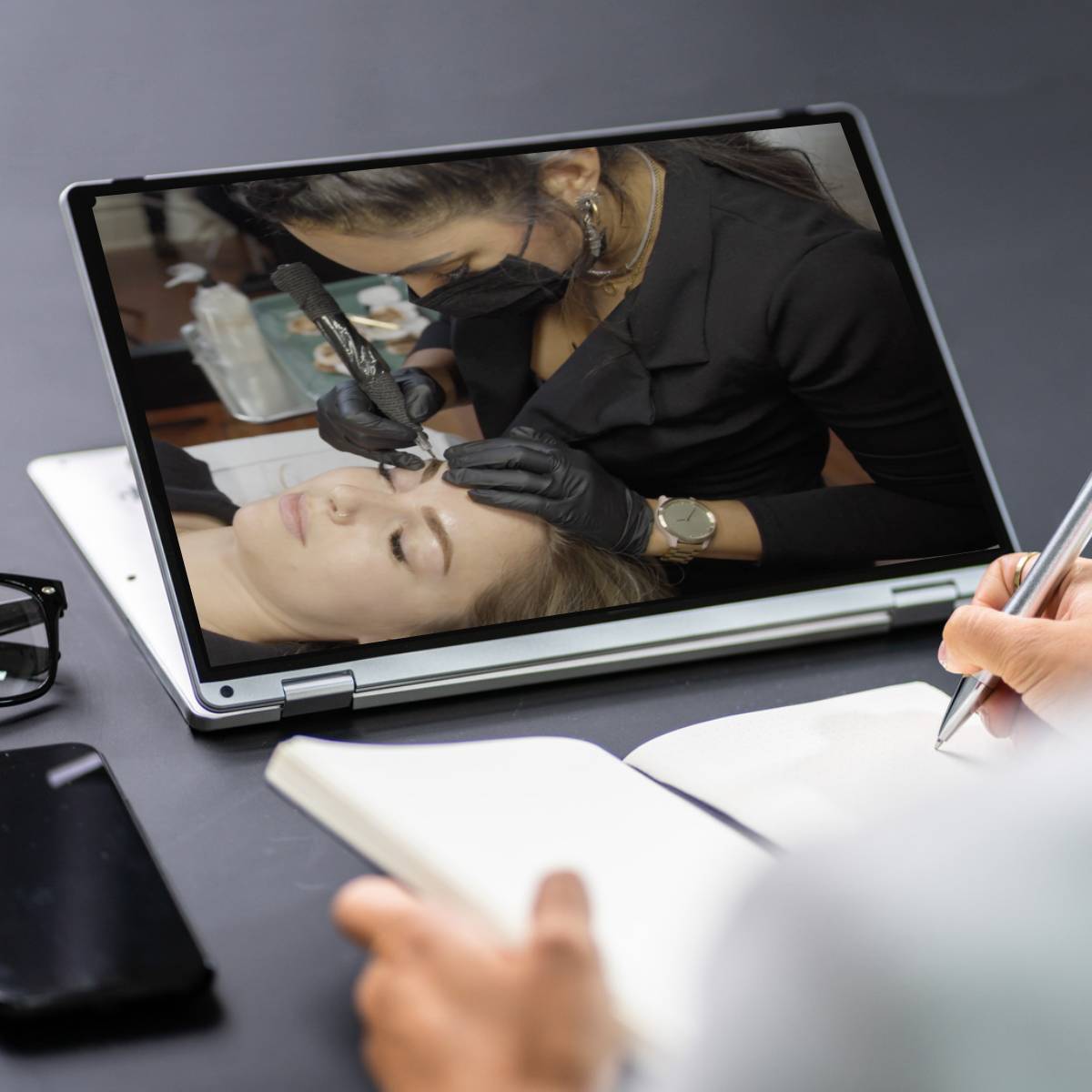 Rojin of Rouge Ink reviews tattoo technique via a video playing on tablet.