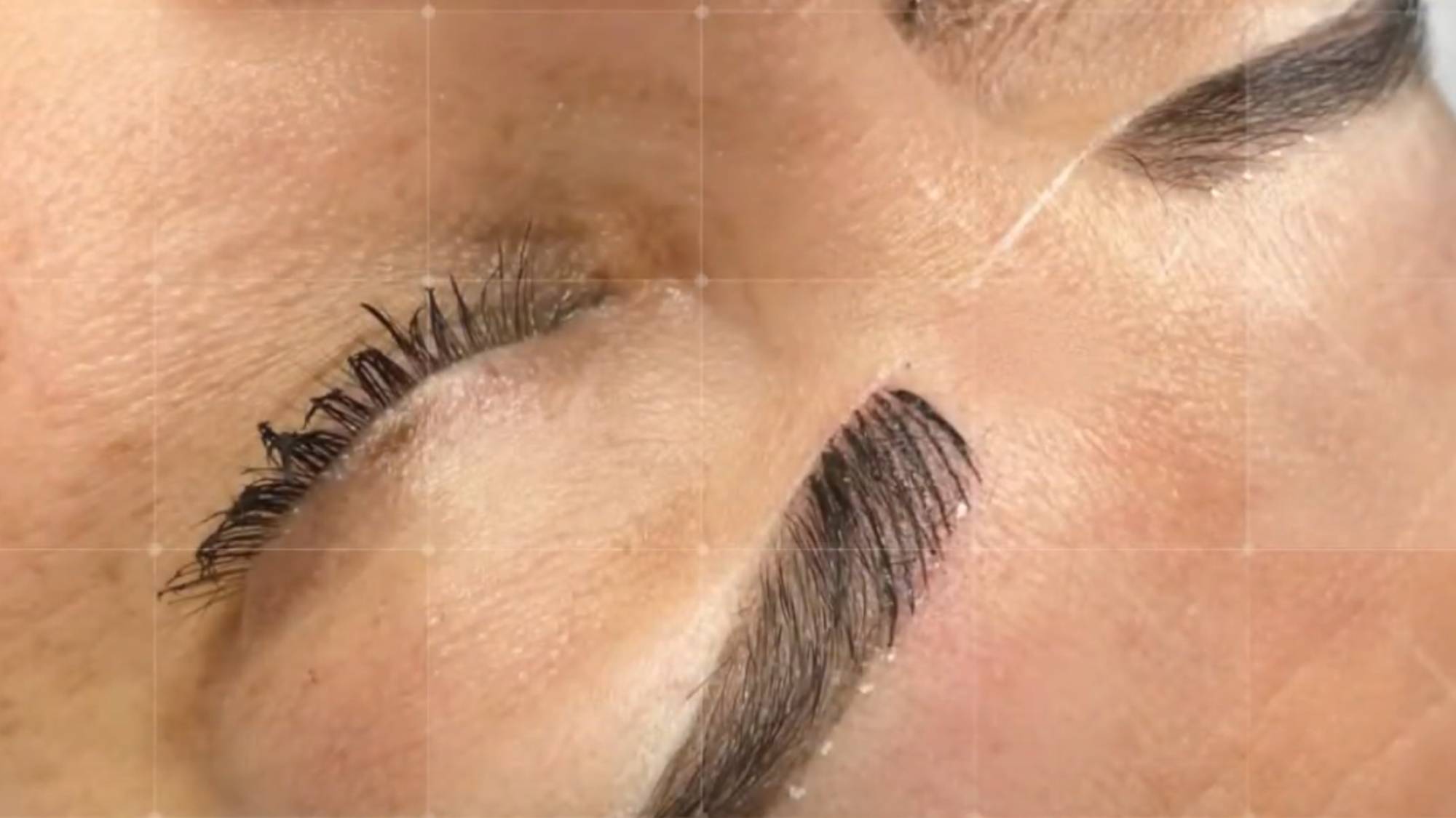 Close-up of microblading technique showing hair-like eyebrow strokes.